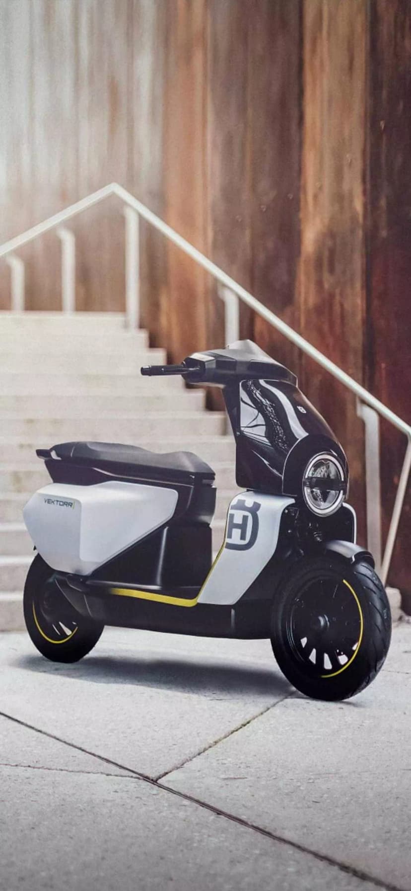 Husqvarna Vektorr electric scooter with matte silver panels parked on a paved urban street during daytime.