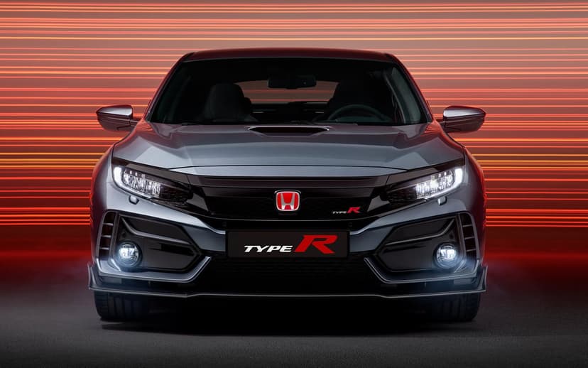 Frontal view of a grey Honda Civic Type R with glowing headlights against orange horizontal light streaks.