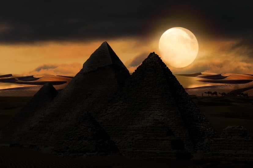Great Pyramids silhouetted against a massive full moon in a starry night sky with camels on desert sand dunes.