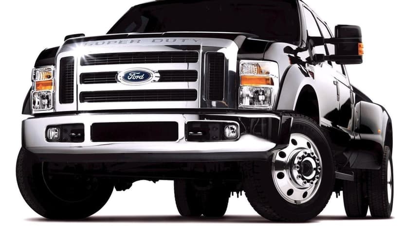 Black Ford Super Duty dually truck with a large chrome grille and shiny wheels on a white background.