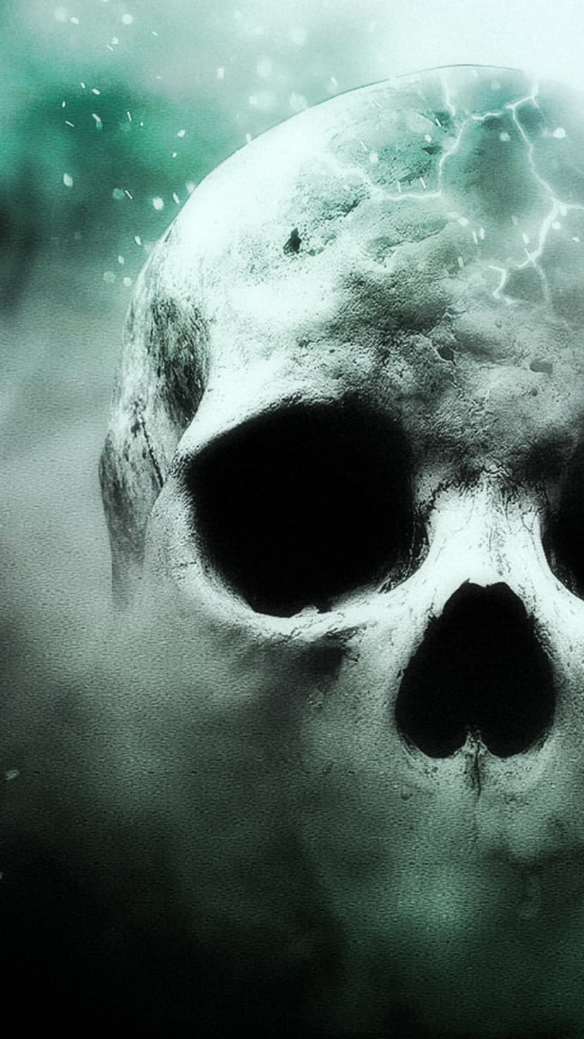 Human skull with cracked forehead glowing from within while surrounded by thick fog and floating green particles.
