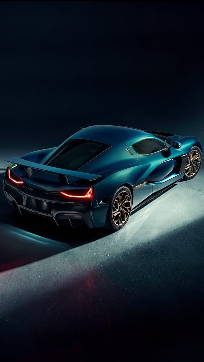 Teal hypercar with a large rear wing, bronze wheels, and red LED taillights against a dark studio background.