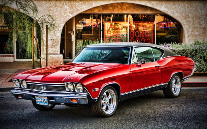 Red 1968 Chevrolet Chevelle SS 396 parked on a street with a glowing neon bail bond sign in the background.