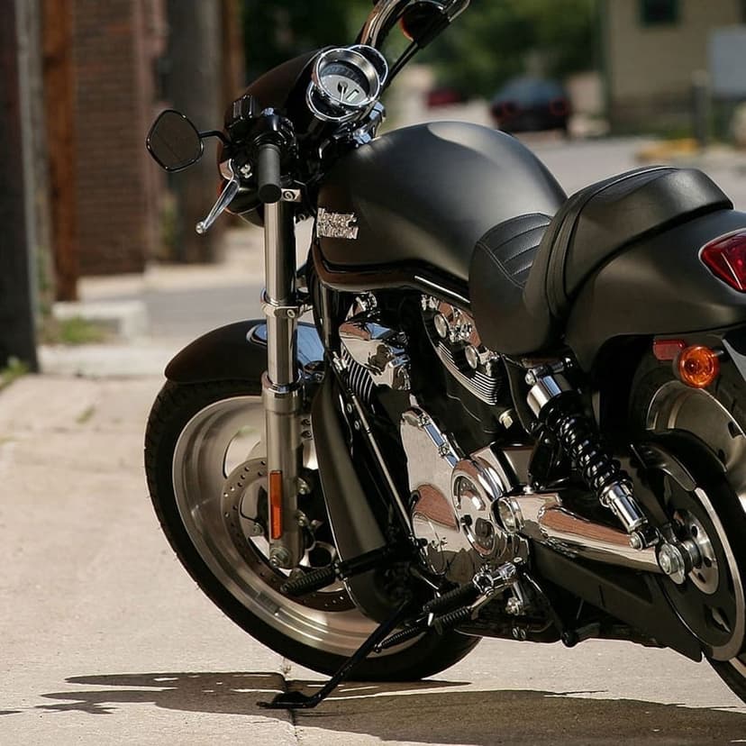 Matte black Harley-Davidson motorcycle with chrome accents parked on a brick-lined street at a low-angle view.
