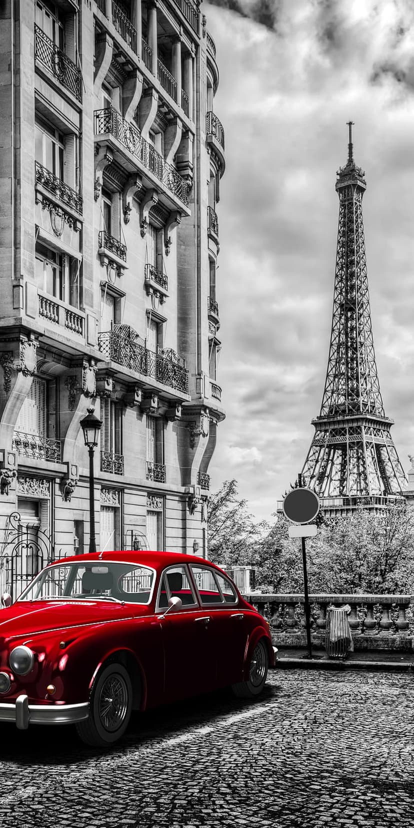 Red vintage car on a cobblestone Paris street with the Eiffel Tower in a monochrome background for mobile.