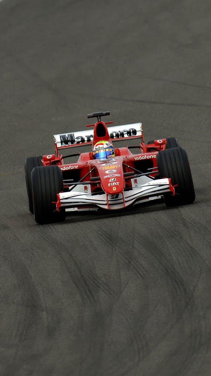 Ferrari Formula 1 car with sponsor logos races on a dark asphalt track from a low-angle perspective.