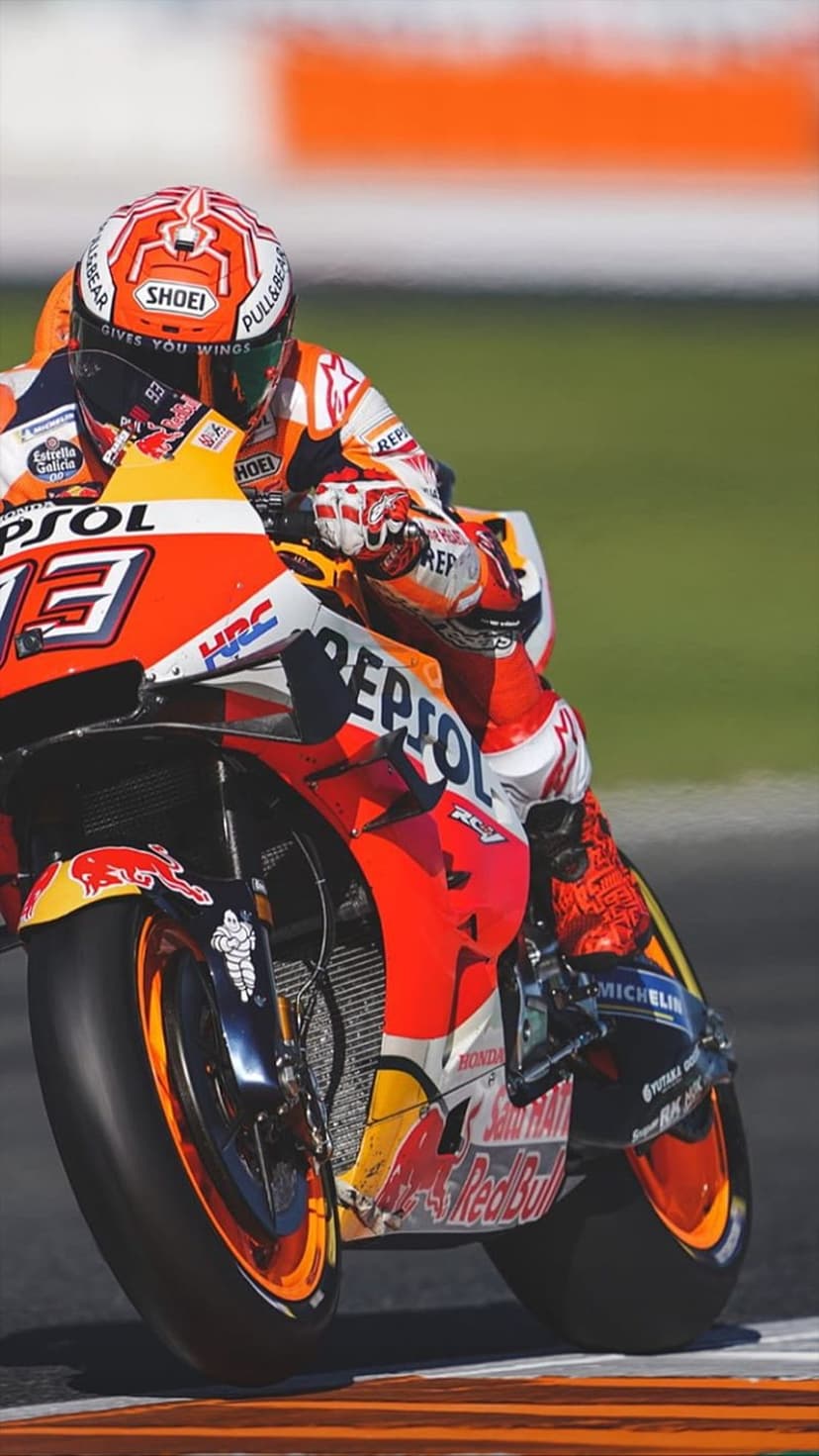 Marc Marquez leans deep into a racetrack corner on a Repsol Honda motorcycle under bright sunlight.