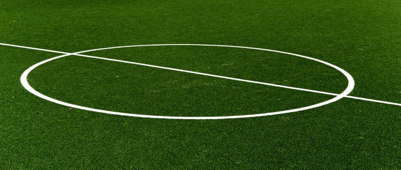 Green artificial soccer turf with a bright white center circle and straight line marking across the field.