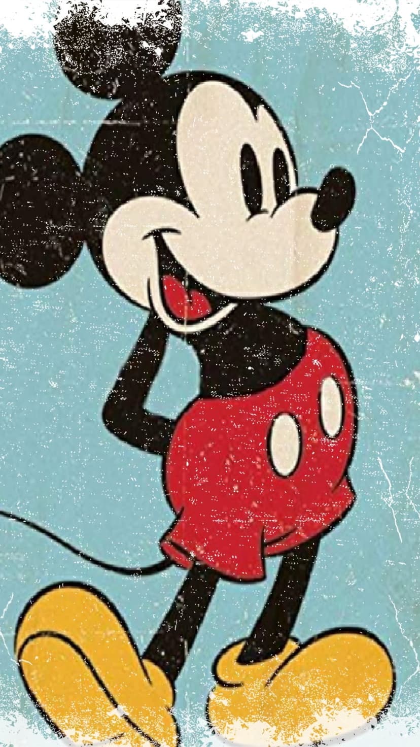 Mickey Mouse in red shorts and yellow shoes stands against a textured light blue background in a vintage pose.