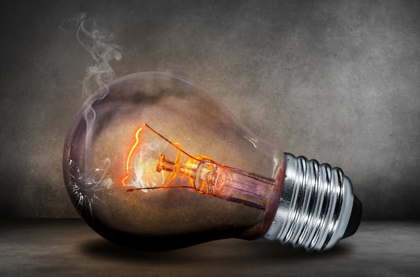Incandescent bulb with a glowing orange filament and swirling smoke against a dark textured background.