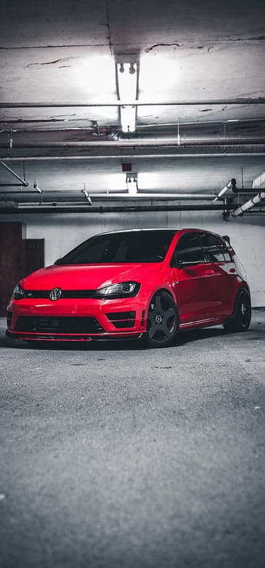 Red Volkswagen Golf R in dimly lit parking garage
