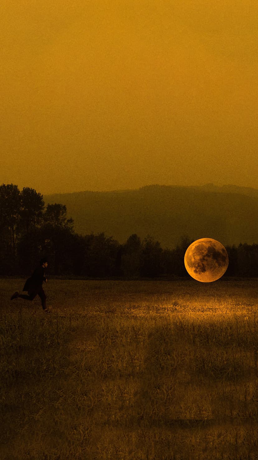 A person runs toward a giant glowing moon across an ochre field with distant hills and silhouetted trees.