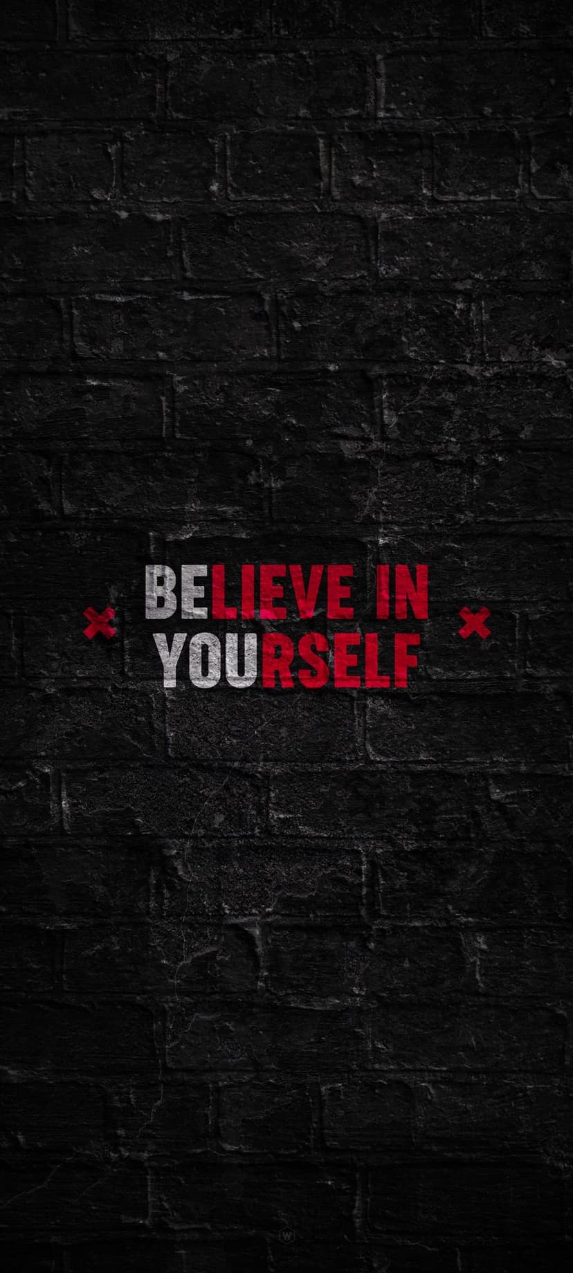 Believe in Yourself text in white and red fonts centered on a dark, weathered black brick wall with deep shadows.