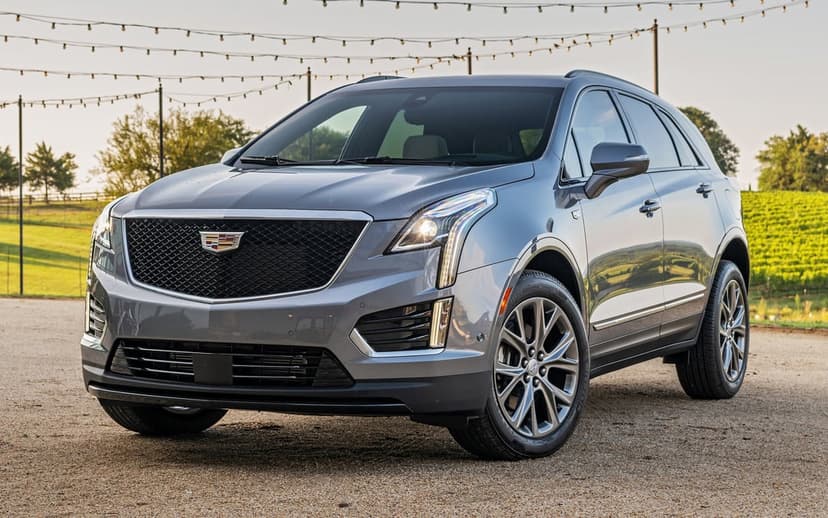 Silver Cadillac XT5 luxury SUV parked on gravel with vineyard background and overhead string lights.