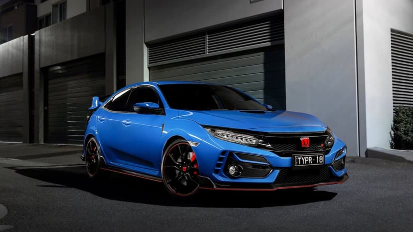Blue Honda Civic Type R with red accents parked in front of a dark building with night lighting.