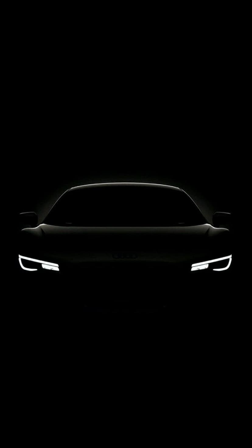 Sports car silhouette with glowing white LED headlights isolated against a solid pitch-black background.