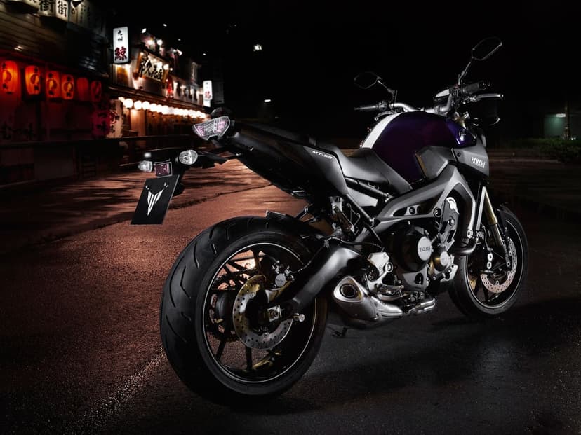 Yamaha MT-09 motorcycle on a wet night street in front of glowing orange lanterns and a Japanese building.
