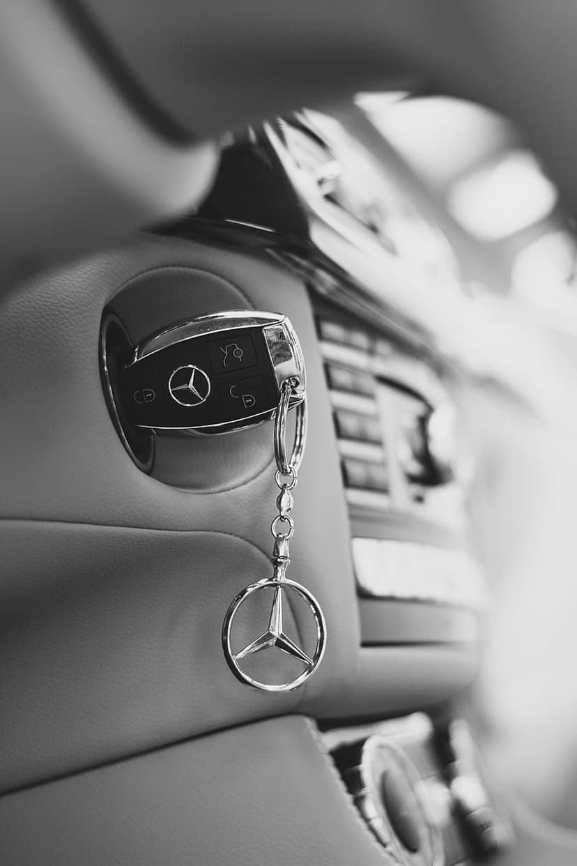 Mercedes-Benz key in an ignition switch with a polished silver star logo keychain on a dark dashboard.