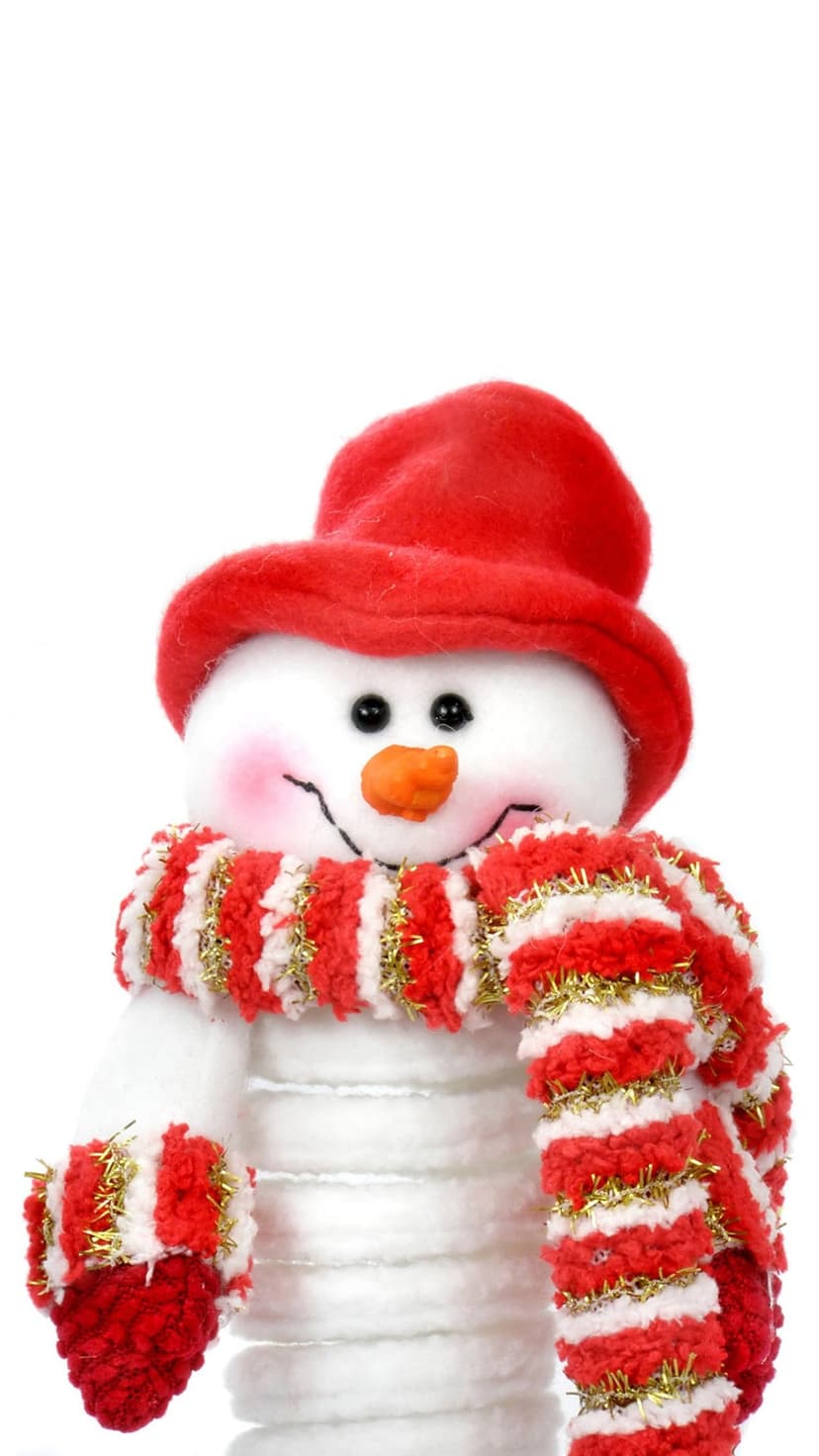 Plush snowman wearing a red fuzzy hat and striped scarf with gold tinsel accents against a white background.
