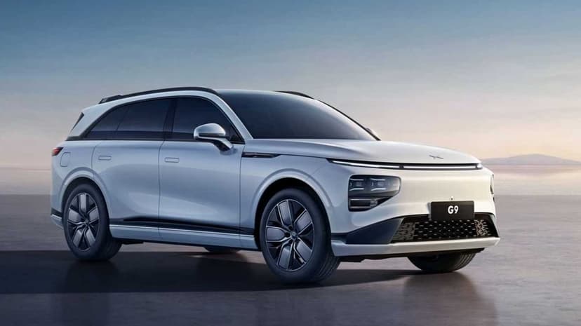 Silver XPeng G9 electric SUV parked on a smooth surface during a soft coastal sunset with clean lines.