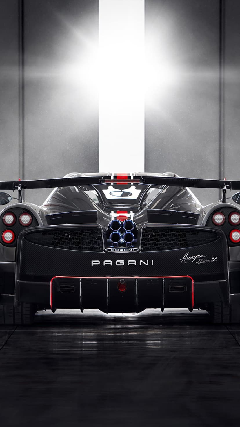 Pagani Huayra BC Roadster rear view with quad exhaust pipes and carbon fiber trim under a bright top spotlight.
