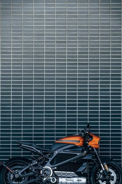 Orange Harley-Davidson LiveWire parked against brick wall