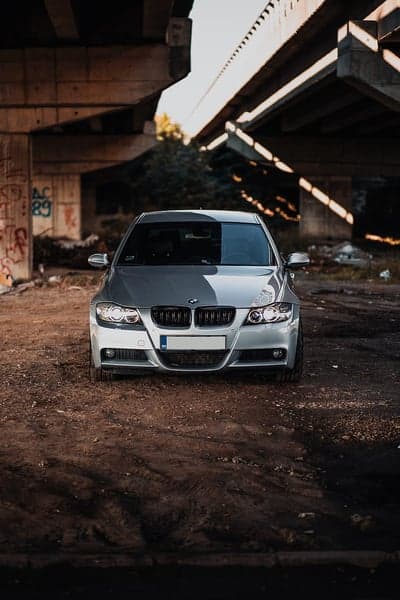 Silver BMW Sedan Under Urban Overpass Phone Wallpaper