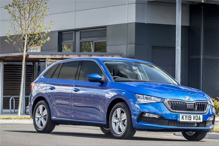 Blue Skoda Scala parked in front of a modern grey building during a bright, clear day with sharp reflections.
