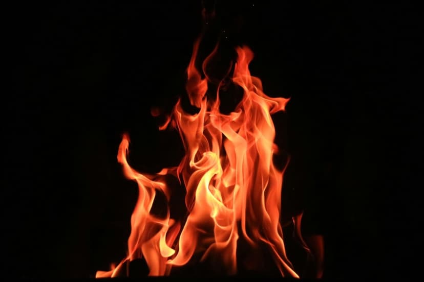 Luminous orange and yellow flames flicker with wispy edges against a solid black background in high contrast.