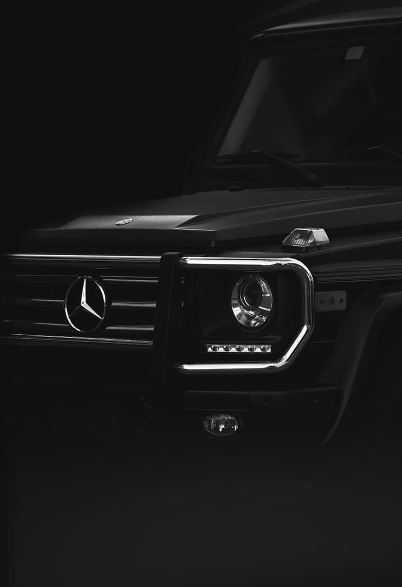 Mercedes-Benz G-Class front grille and LED headlights highlighted by dramatic black and white studio lighting.