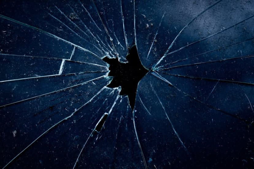 Fractured glass shards radiate from a central impact point with intricate midnight blue radial cracks.