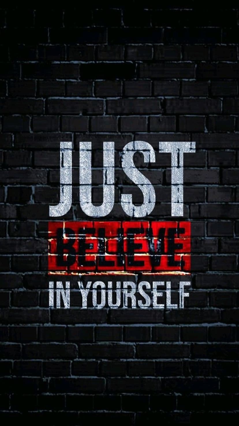 Just Believe In Yourself text in white lettering centered on a dark, weathered masonry brick wall surface.