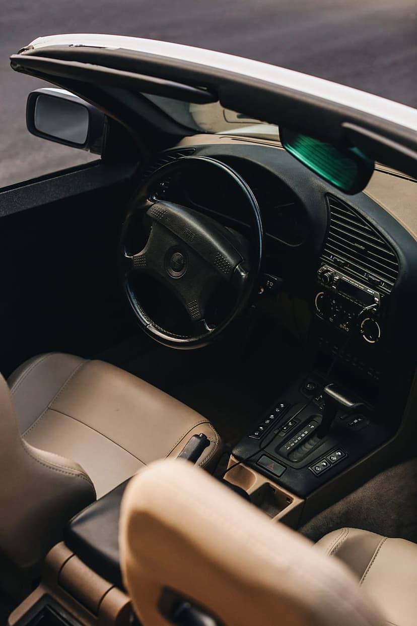 BMW E36 cabin featuring tan leather seats and a classic black dashboard viewed from a vertical perspective.