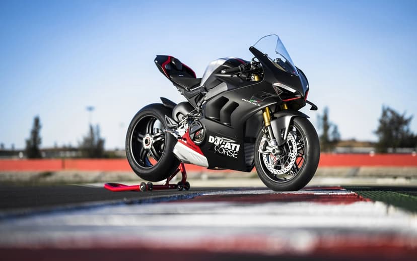 Matte black Ducati Panigale V4 SP2 motorcycle on a racetrack under a clear sky with gold front forks.