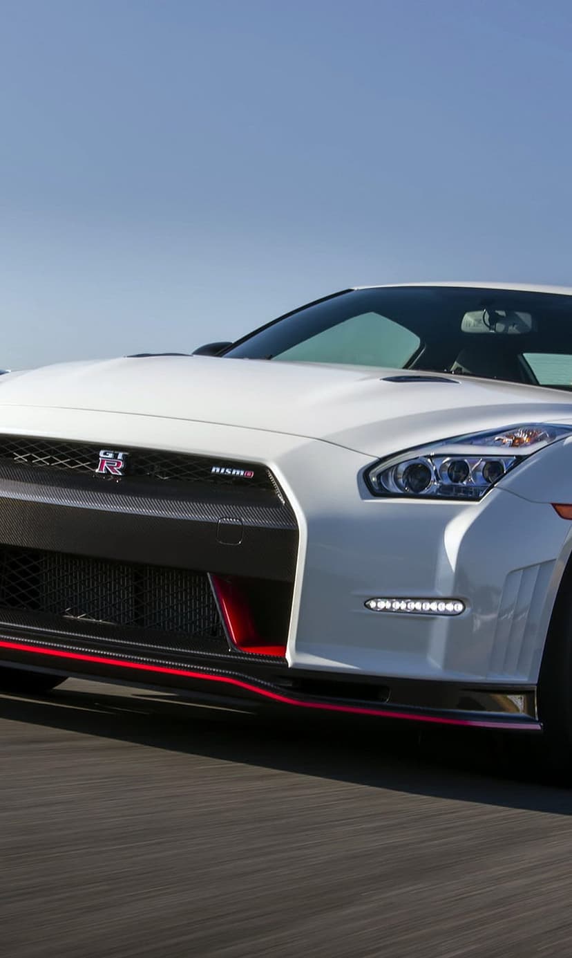 Nissan GT-R Nismo with a white exterior, red trim on carbon fiber aero, and a honeycomb black front grille.
