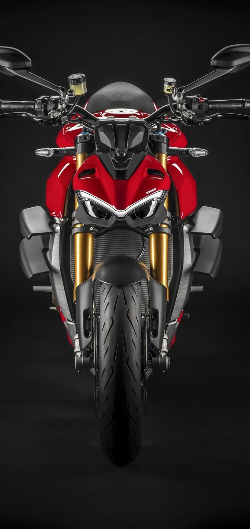 Front view of a red Ducati motorcycle with gold forks and sharp LED headlights on a black studio background.