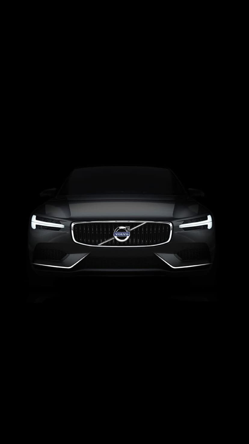 Volvo front grille with illuminated LED headlights and silver logo centered on a solid black background.