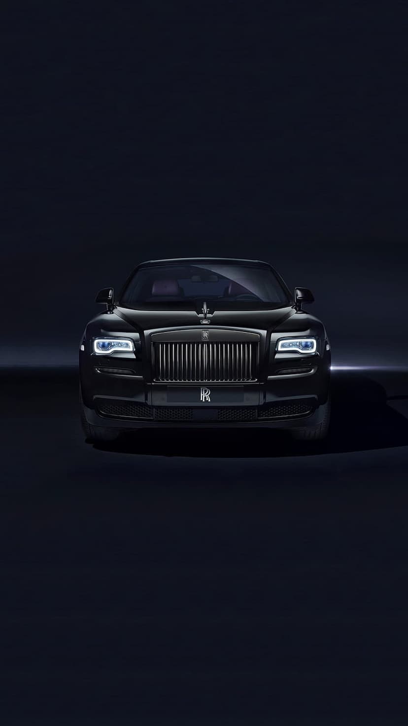 Rolls-Royce Ghost front grille and Spirit of Ecstasy ornament illuminated against a dark, minimalist background.