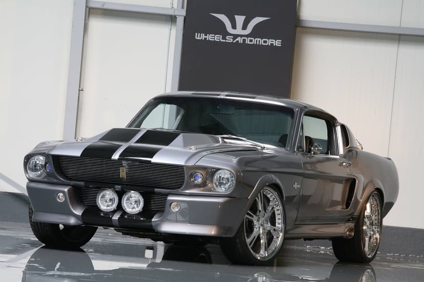 Silver Shelby GT500 Eleanor with black racing stripes and chrome wheels in a clean showroom environment.