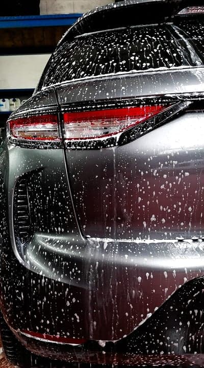 Suds-covered car rear in detail, car wash.