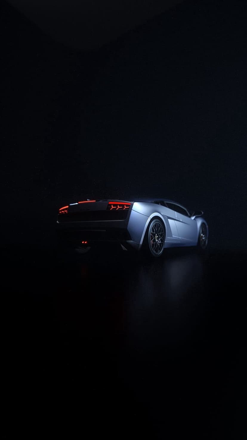 Silver sports car with glowing red taillights and metallic rims parked in a dark, low-key lighting environment.
