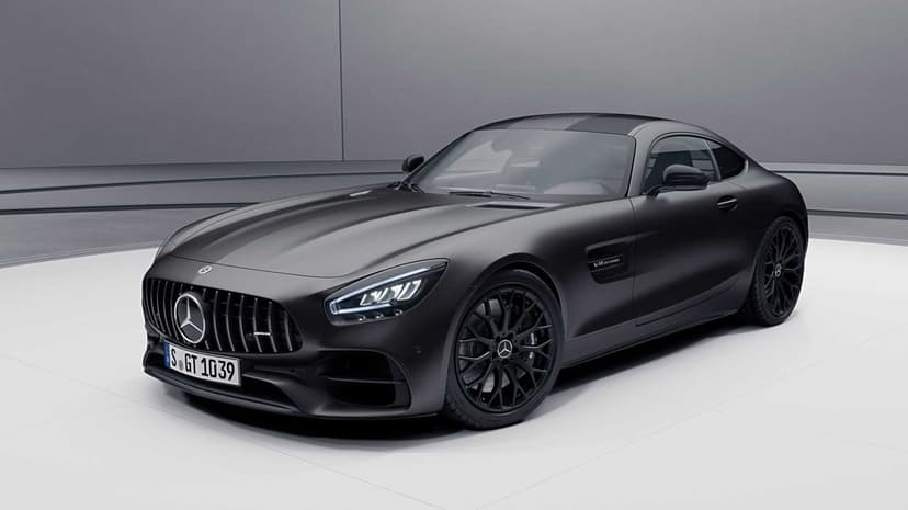 Matte black Mercedes-AMG GT with LED headlights and multi-spoke wheels in a minimalist studio background.