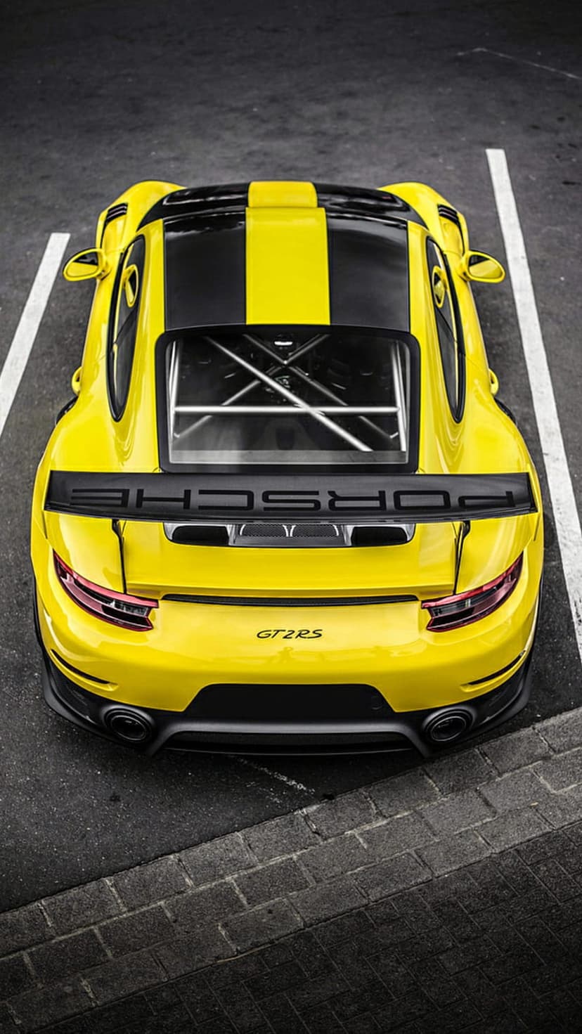 Yellow Porsche GT2 RS with black stripes viewed from above featuring a large rear wing and Porsche branding.