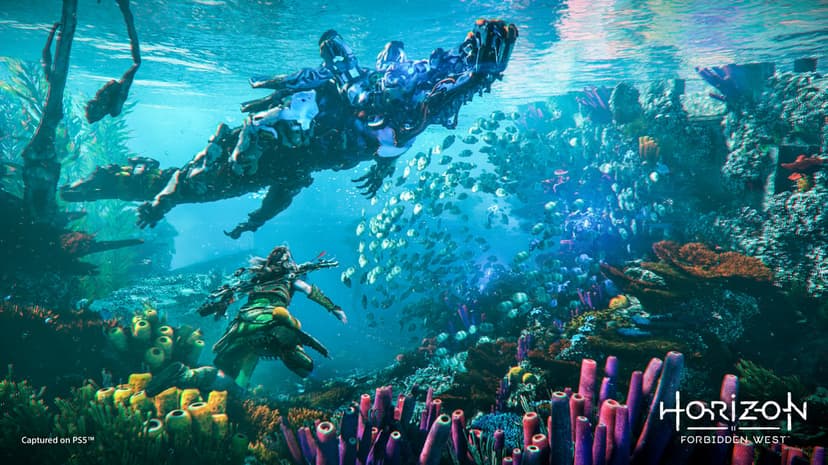 Aloy swims underwater near a large mechanical crocodile through a colorful coral reef with schools of fish.