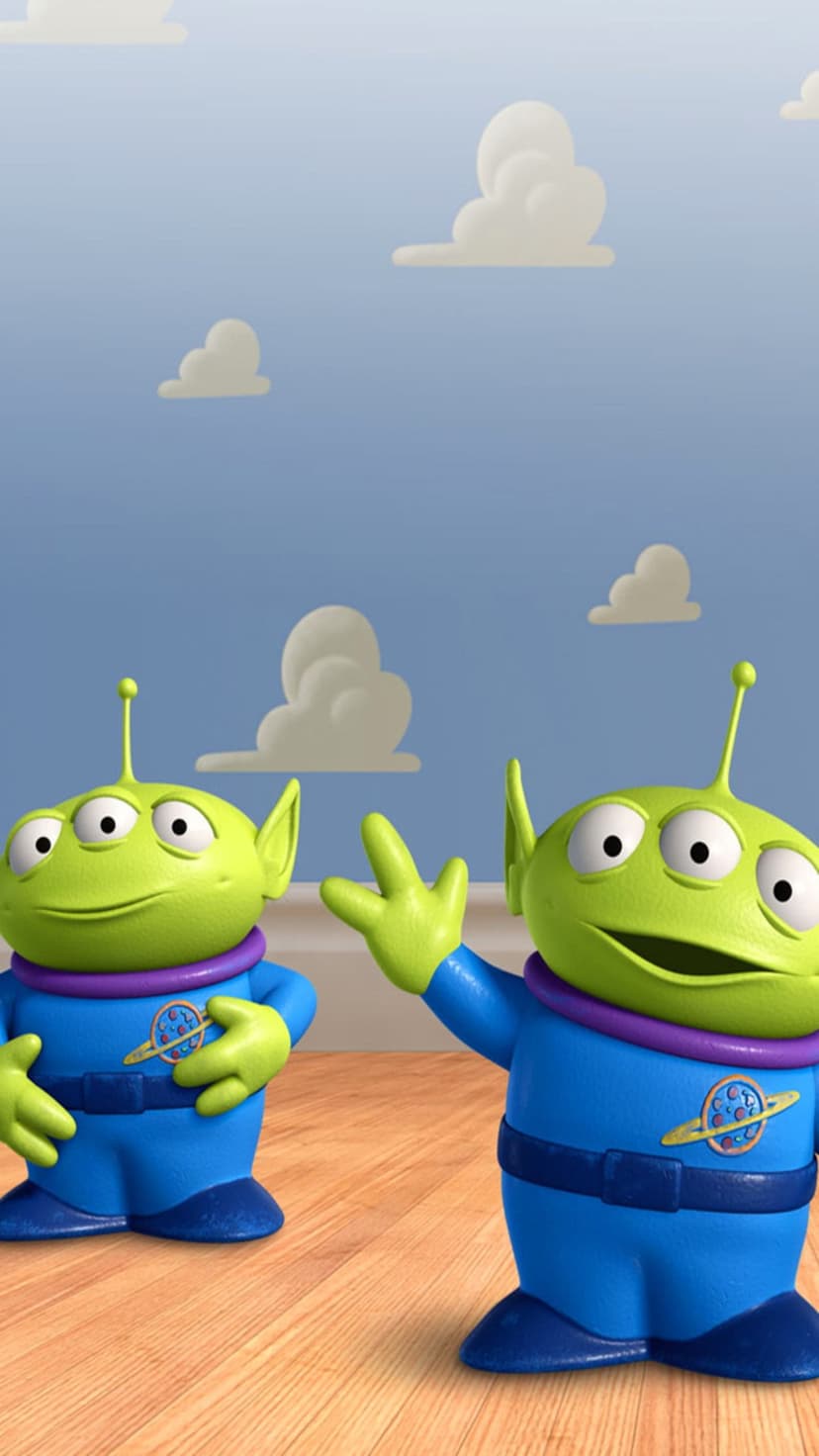 Two green three-eyed Toy Story aliens in blue suits stand on wood against a sunny sky with fluffy white clouds.