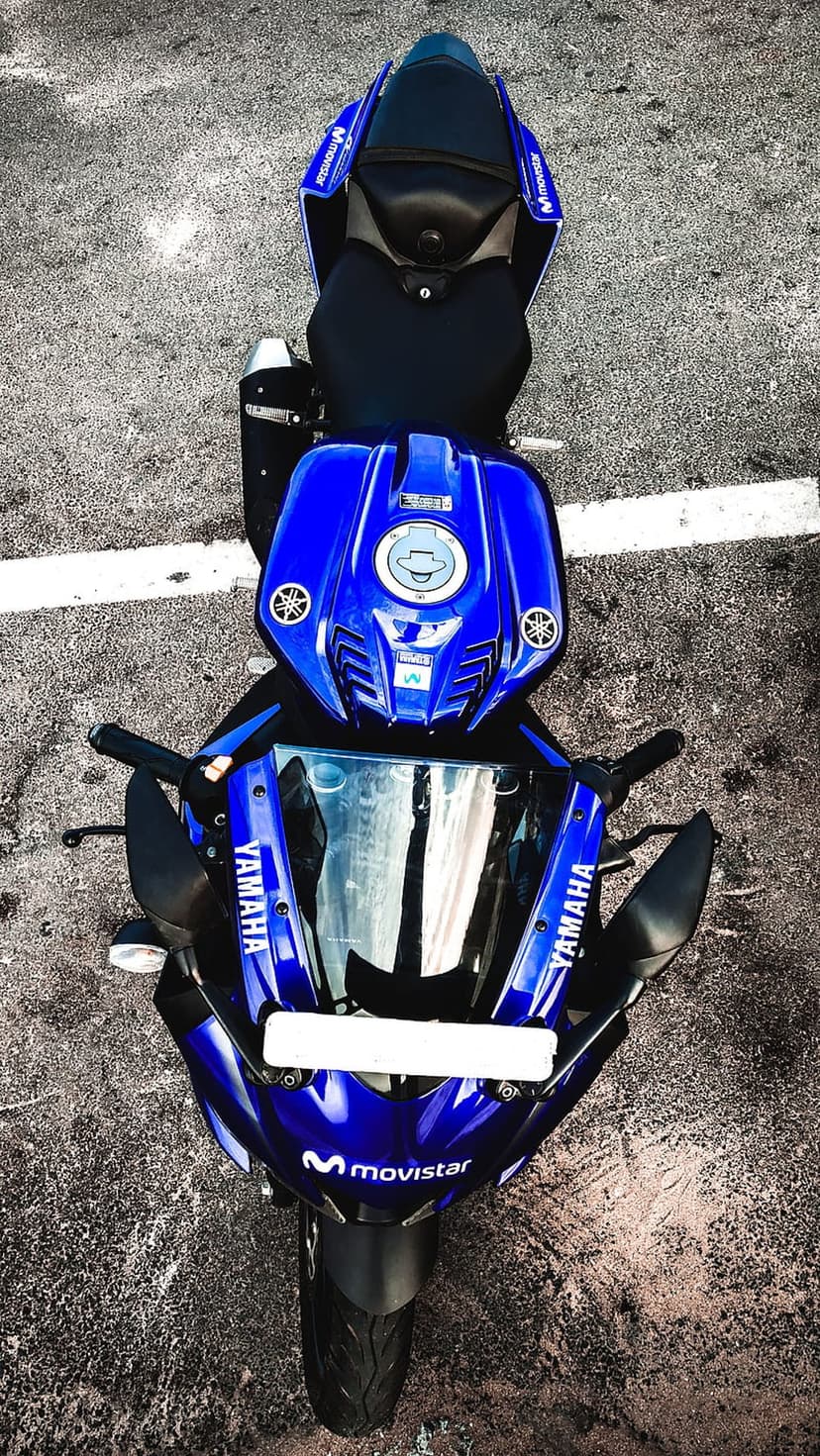 Blue Yamaha R15 sportbike with Movistar branding parked on a dark asphalt road surface from an overhead view.