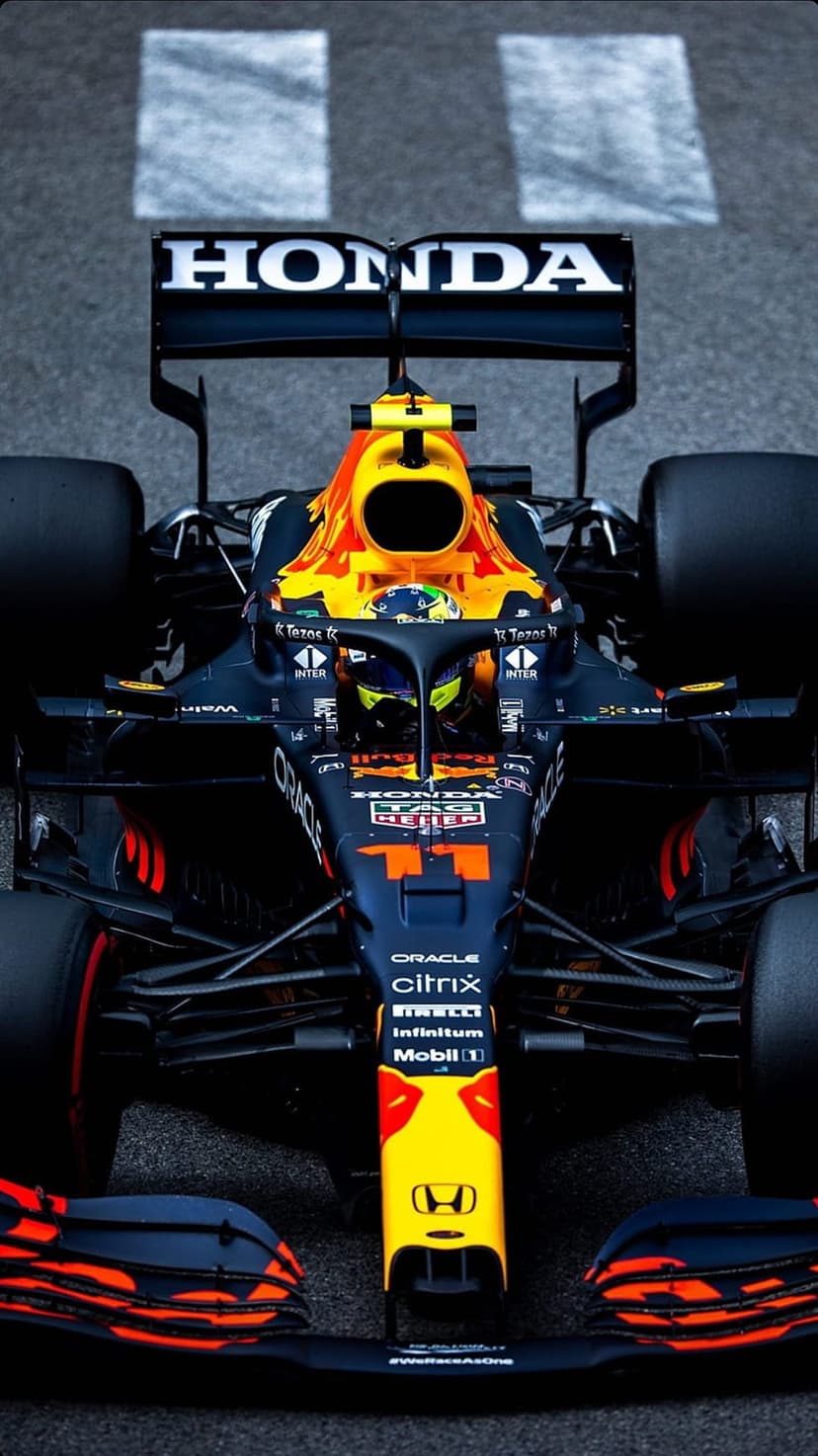 Red Bull F1 car with Honda branding displays front wing aerodynamics on a grey asphalt racetrack background.