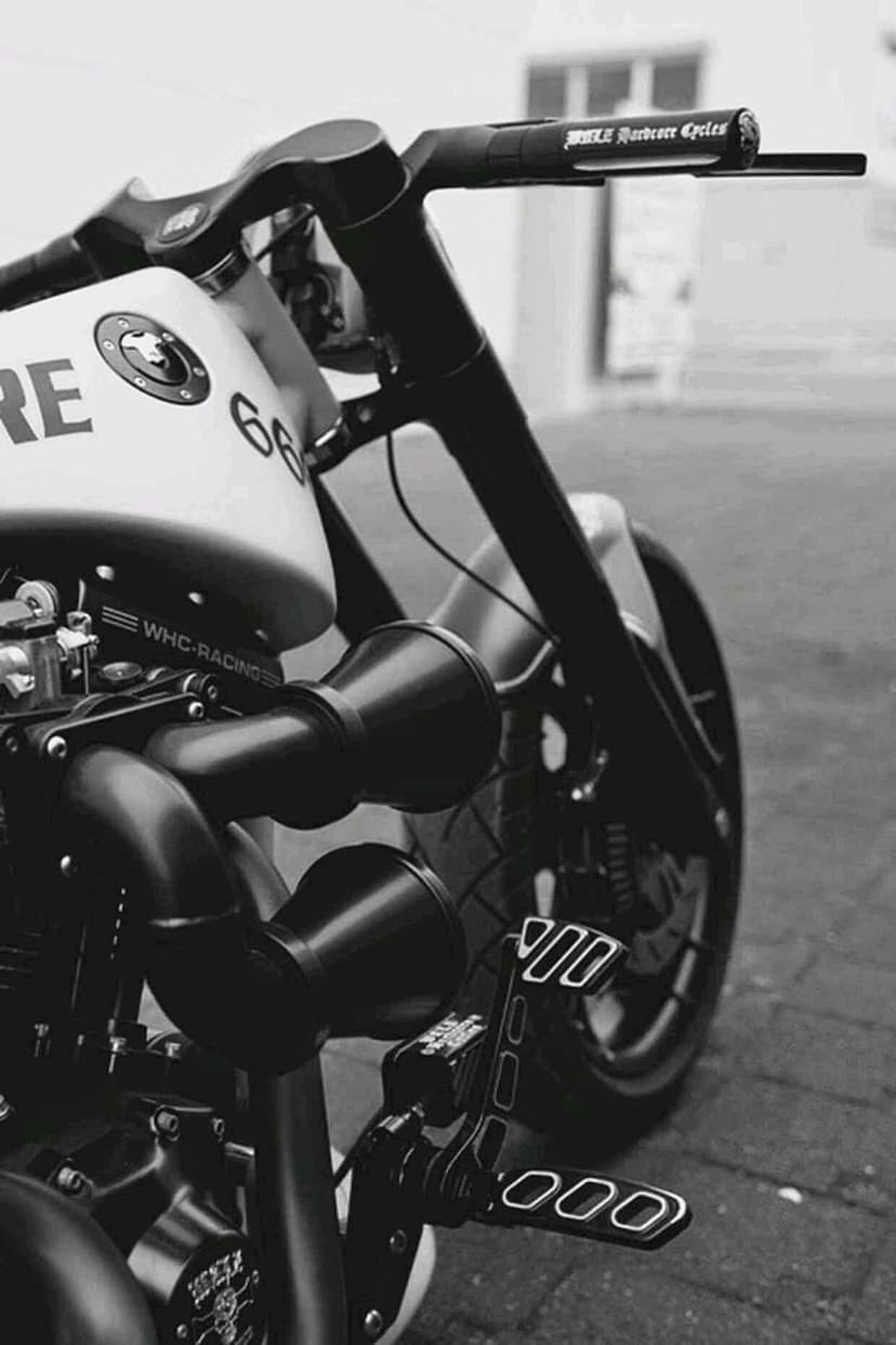 Custom Harley motorcycle handlebars and exhaust pipes with the number 66 on the tank in black and white.