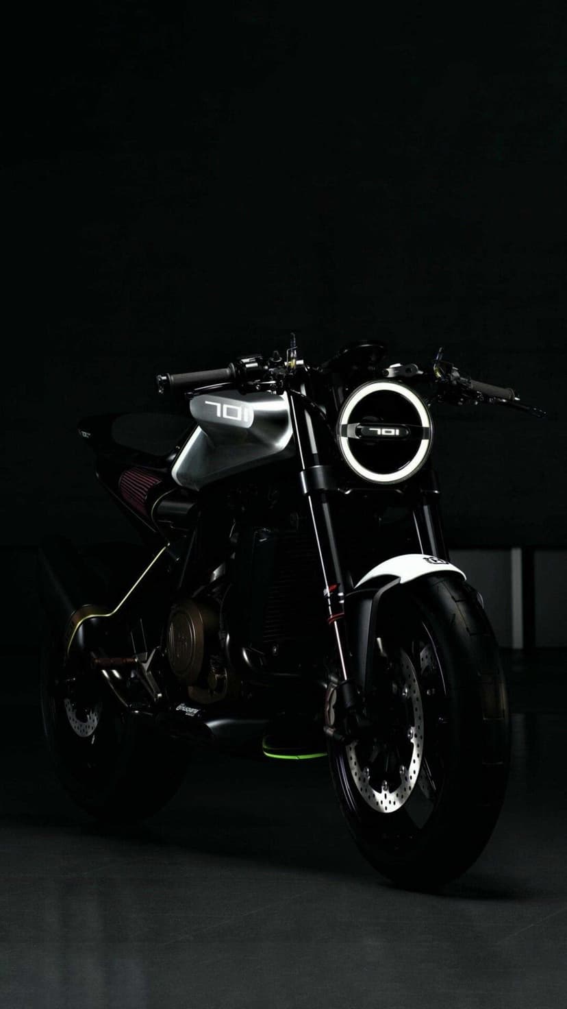 Black motorcycle with a circular 701 LED headlight glows against a dark background in a vertical studio shot.