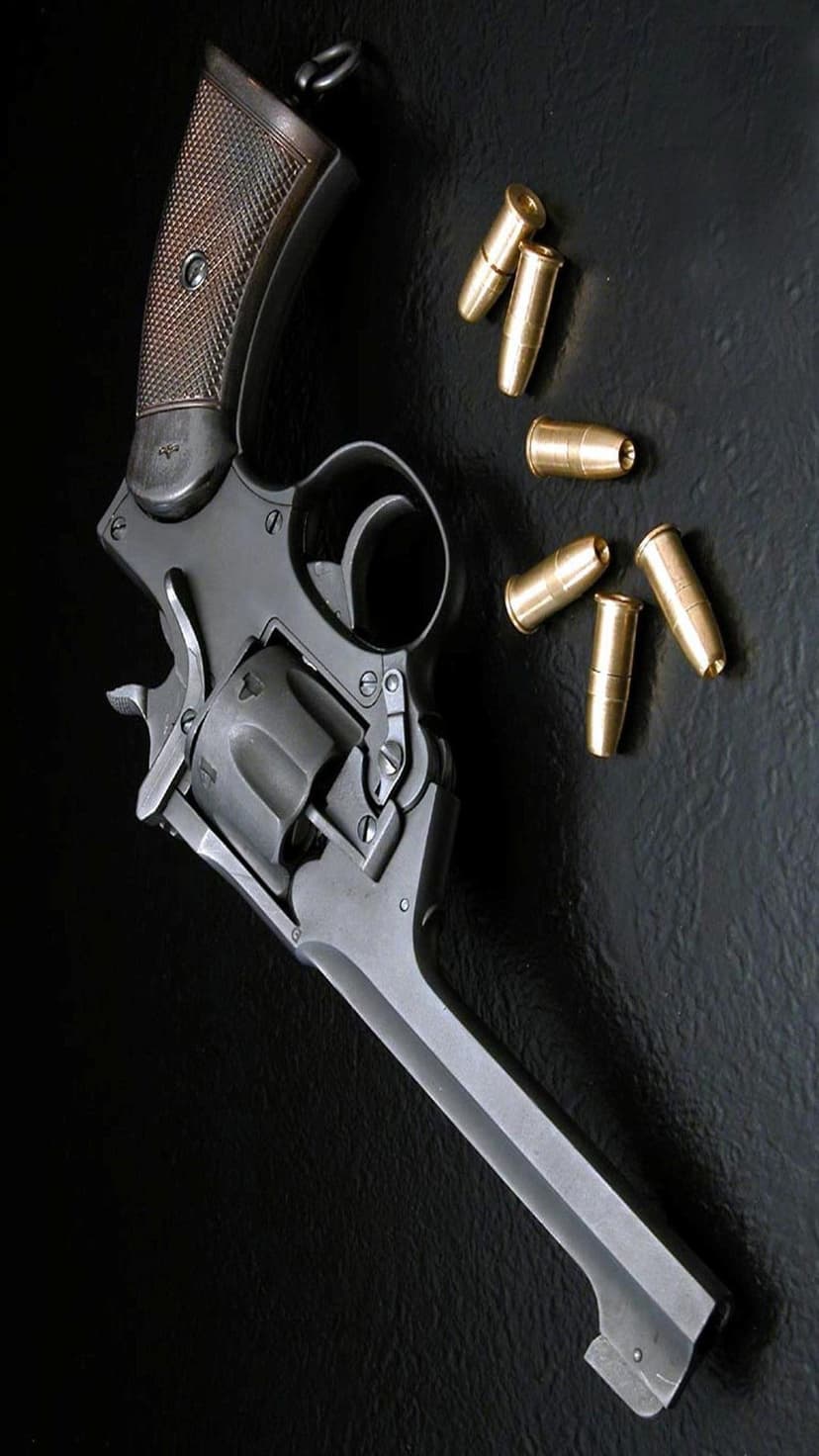 Steel vintage revolver with a checkered wooden grip next to several brass bullets on a black textured surface.